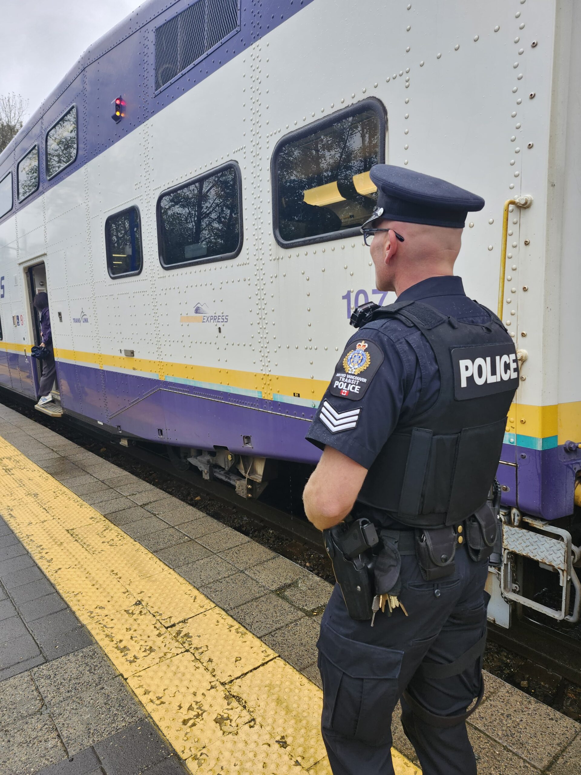 A police officer stands at a West Coast Express station with the train in the background